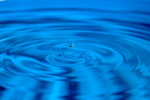 Macro droplet falls on the surface of water — Stock Photo, Image