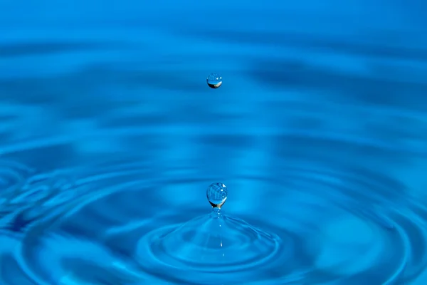 Macro droplet falls on surface of water — Stock Photo, Image