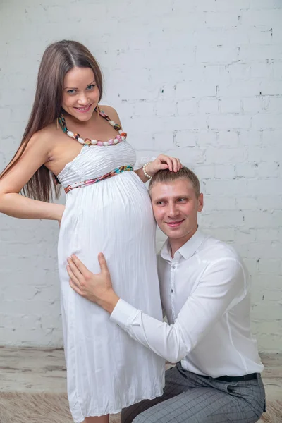 待っている赤ちゃん。幸せな男を置く彼の耳は妻の腹 — ストック写真