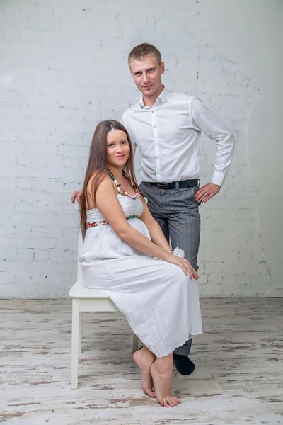 Esperando al bebé. Hombre y esposa embarazada en silla —  Fotos de Stock