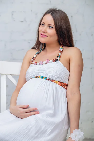 Woman sit on the chair holding his belly — Stock Photo, Image