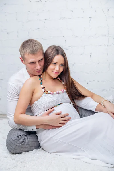 Мужчина обнимает беременную жену на полу — стоковое фото