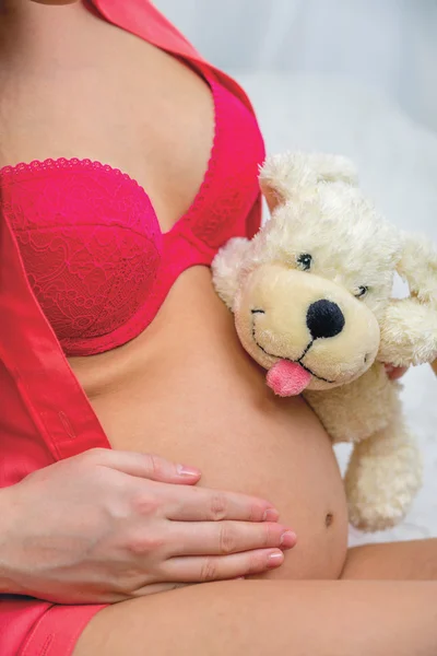 Soft toy on the stomach of a pregnant girl — Stock Photo, Image