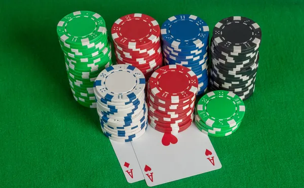 Par de ases e fichas de poker empilhar na mesa verde — Fotografia de Stock