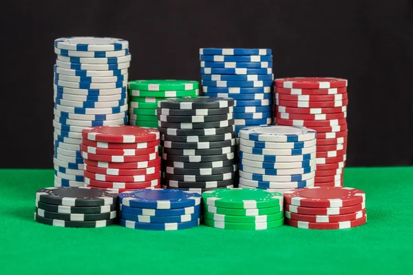 Pilha de fichas de poker na mesa verde fundo preto — Fotografia de Stock