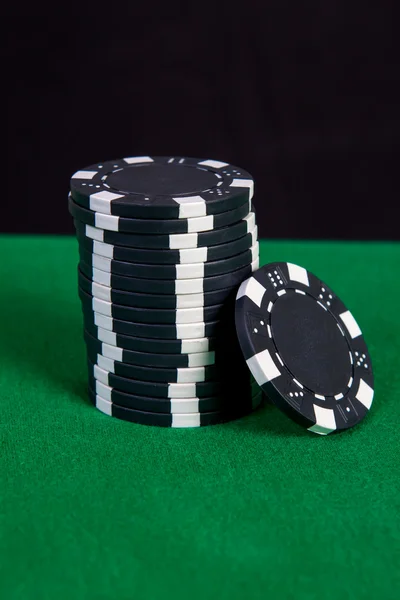 Stack of black chips on a green playing table — Stock Photo, Image