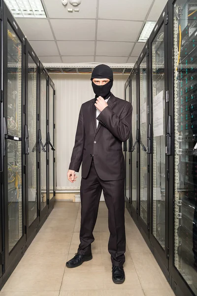 Ladrón en la máscara negra hackear la sala de servidores descargar datos en el ordenador portátil —  Fotos de Stock