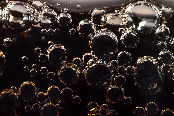 Macro black bubbles on  the glass wall of cola