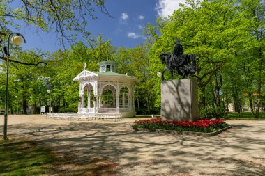 White wooden music pavilion and monument - statue of the founder of the spa - Austrian Emperor Franz I in the spa park in the center of Frantiskovy Lazne (Franzensbad) - Czech Republic, Europe