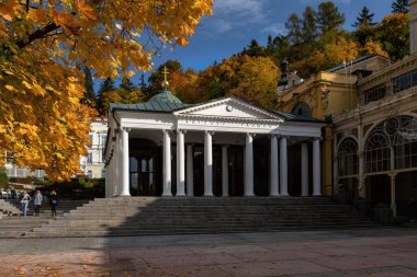 Çek kaplıcasında sonbahar atmosferi Marianske Lazne (Marienbad) - maden suyu pavyonu inşaatı Çapraz Bahar - güneşli sonbahar günü, mavi gökyüzü ve sarı ağaç yaprakları