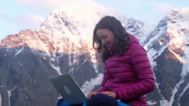 Señora se comunica a través de ordenador portátil sentado en la cima de la colina y sonríe — Vídeos de Stock