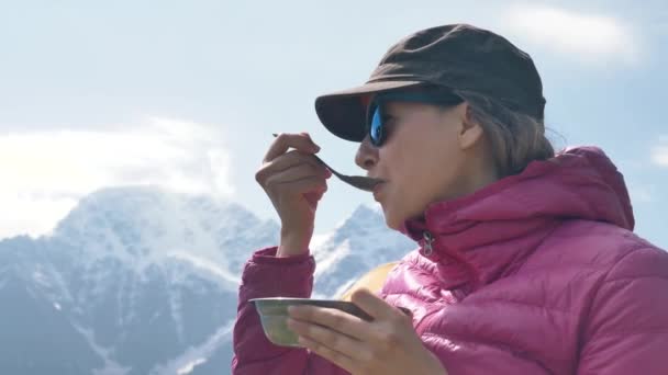 Lady come de cuenco de metal con carne de cerdo contra las montañas — Vídeo de stock