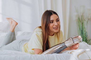 Biyonik protez kollu bir kadın blogcu bir internet yayınını yönetiyor ya da bir konuyu kaydediyor ya da yatakta uzanırken arkadaşlarıyla görüntülü iletişim kuruyor.