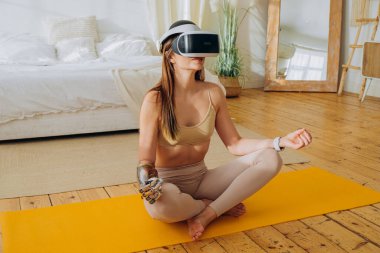 Güneşli odada biyonik protezi ve VR kulaklığı olan bir kadın.