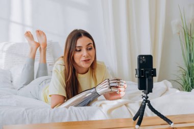 Biyonik protez kollu bir kadın blogcu bir internet yayınını yönetiyor ya da bir konuyu kaydediyor ya da yatakta uzanırken arkadaşlarıyla görüntülü iletişim kuruyor.