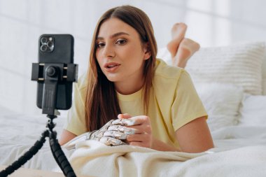 Biyonik protez kollu bir kadın blogcu bir internet yayınını yönetiyor ya da bir konuyu kaydediyor ya da yatakta uzanırken arkadaşlarıyla görüntülü iletişim kuruyor.