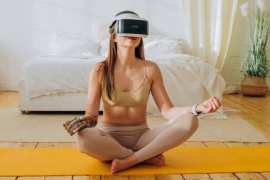 Güneşli odada biyonik protezi ve VR kulaklığı olan bir kadın.