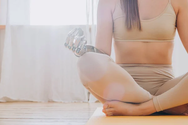 Peaceful woman with prosthesis arm meditates in sunny room