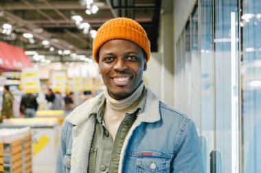 Süpermarkette kot ceketli neşeli Afro-Amerikalı adam