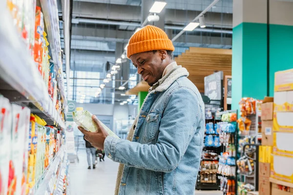 Думаючий афро-американський чоловік вибирає сік в магазині. — стокове фото