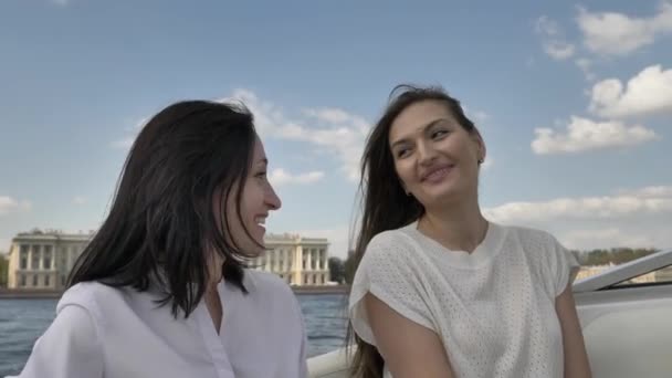 Усміхнена молода жінка вгорі розмовляє з подругою брюнетки на човні — стокове відео