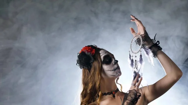 Model met schedel make-up poses met dreamcatcher in handen — Stockfoto