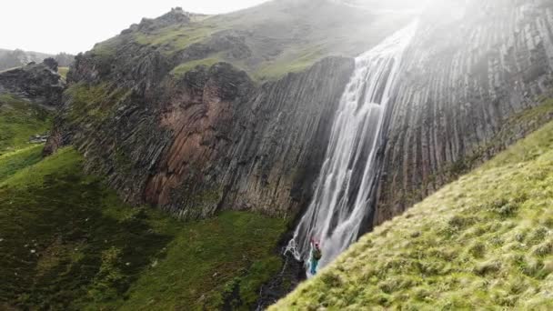 Dame se tient sur la colline verte près de cascade montagneuse — Video