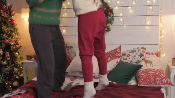 Cansados y felices mamá y su hija saltaron a la cama y se tumbaron a descansar, sobre el fondo de las decoraciones navideñas — Vídeos de Stock