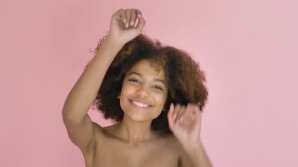 Joven bonita mujer de piel oscura bailando vigorosamente sobre fondo rosa de cerca — Vídeo de stock