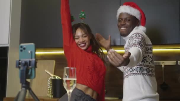 Divertida pareja afroamericana bailando en la cocina y grabando los bailes en el teléfono, familia celebrando la fiesta de Navidad en casa — Vídeo de stock