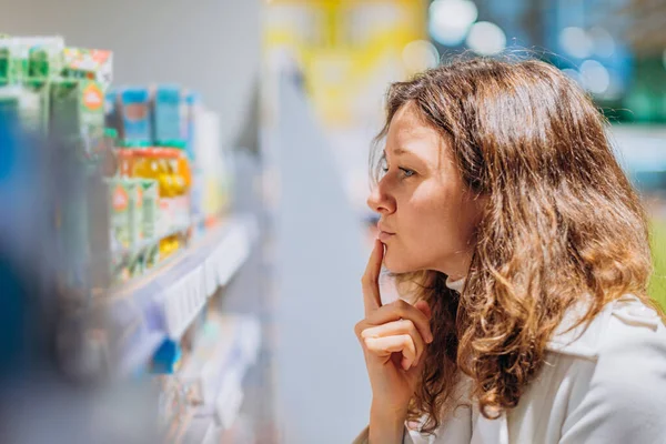 Mutter liest Zusammensetzung von Babynahrung, untersucht Zutaten im Supermarkt — Stockfoto