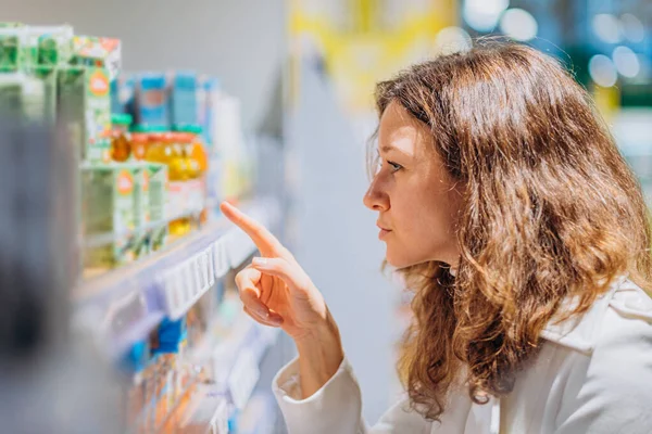 Жінка читає композицію на дитячому соку в супермаркеті — стокове фото