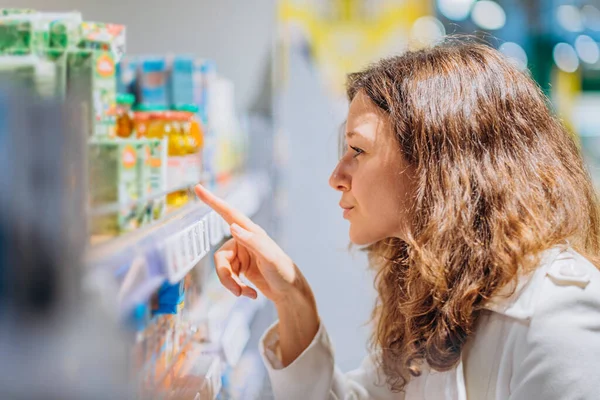 Frau liest Komposition auf Babysaft im Supermarkt — Stockfoto