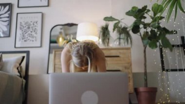 Sarışın kadın dizüstü bilgisayarla esneme hareketleri yapıyor.