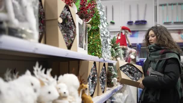 Woman with curly hair buys Christmas decorative wreath — Stock Video