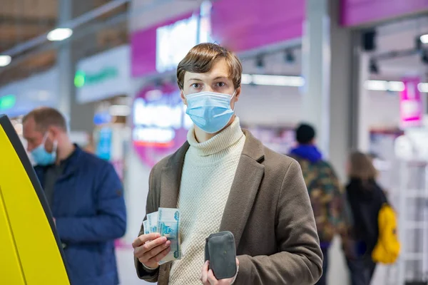 Коротковолосий чоловік дивиться в камеру, тримаючи готівку біля банкомата. — стокове фото