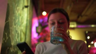 Genç bir kadın kafeteryada yemek yerken sosyal medyada geziniyor.