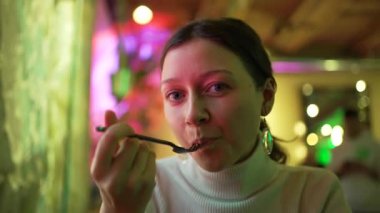 Kadın salata yiyor ve kafede oturmaktan hoşlanıyor.