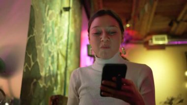 Esmer kadın salata yiyor ve sosyal medyayı telefonla kontrol ediyor.