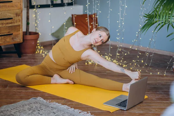 Молода жінка займається вправами йоги на килимку з онлайн лайном — стокове фото