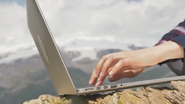 Close-up female hands are typing on a laptop keyboard in the mountains — Stockvideo