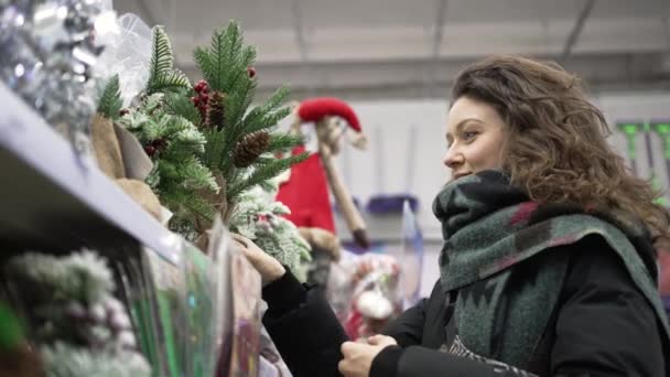 Brunette-haired woman chooses decorations for Christmas — Vídeo de Stock