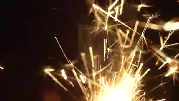Sparks of sparkler shining brightly in dark studio room — стоковое видео