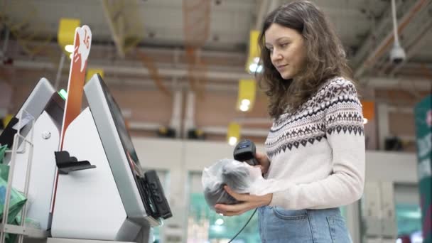 A young woman at the self-service checkout in a grocery supermarket makes purchases — Stockvideo