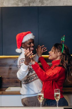 Siyah erkek ve beyaz kadın Noel atmosferinde dans ediyorlar.