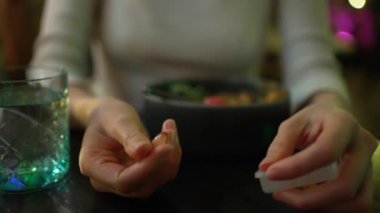 Genç bir kadın akşam yemeğinden önce bir bardak suyla ilaç ve içecek yer.