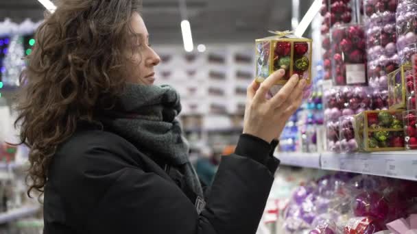 Leuke jonge vrouw kiest Kerstmis speelgoed in de supermarkt — Stockvideo