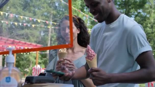 Black man pays for ice-cream with phone talking to brunette — Stock videók