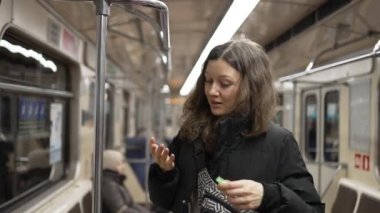 Young woman uses sanitizer after holding handrail in subway
