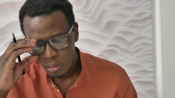 Hombre afroamericano con gafas escribe en cuaderno en la cama — Vídeos de Stock